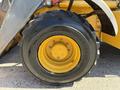 2013 John Deere 710K front tire with a yellow rim and a rugged black tread showing wear and tear