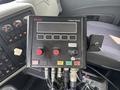 A control panel with buttons and levers labeled for spinner and conveyor functions, featuring a digital display and multiple connected hoses
