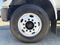 A close-up of a black tire mounted on a white wheel from a 2004 Ford F-750 featuring multiple lug nut holes and the brand name Strong Guard on the sidewall