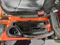 Close-up of the control panel of a 2012 Kubota F3680 featuring a steering wheel lever throttle and a cup holder with some debris inside