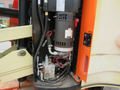 Close-up of the hydraulic system and components of a 2009 JLG E300AJP featuring hoses a motor and a control valve