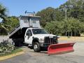 A 2008 Ford F-450 SD dump truck with a raised bed and a red snow plow attached to the front