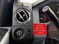 Dashboard controls of a 2012 Ford F-550 with a round air vent a switch for the dump feature and a warning label regarding engine and brake operation