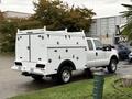 A 2015 Ford F-350 SD truck with a white service body featuring multiple storage compartments and side doors