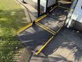 A yellow wheelchair ramp extending from the side door of a 2017 Chevrolet Express van