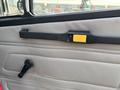 Interior door panel of a 1999 Freightliner FL80 featuring a handle and a window crank in a light-colored fabric