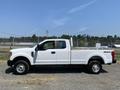 A white 2017 Ford F-250 SD pickup truck is parked with an open bed and a four-wheel drive badge on the side