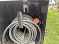 A coiled black hose is stored neatly alongside a red valve on a dark surface