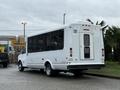 A white 2013 Chevrolet Express bus with a wheelchair access door and large windows on the side