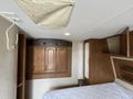 Interior of a 2013 Outdoor Wind River with wooden cabinetry a bed frame and overhead lights