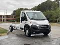 A 2023 RAM Promaster 3500 van with a white exterior and open chassis is parked on a paved area showcasing its boxy design and front grille