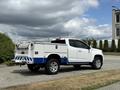 A white 2017 Chevrolet Colorado pickup truck with a utility bed and blue trim parked on a paved surface