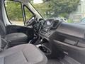 Interior view of a 2023 RAM Promaster 3500 with two grey seating areas and a dashboard featuring a touchscreen display and various control buttons