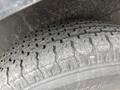 A close-up view of a worn tire with visible tread patterns and dirt on its surface