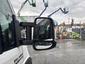 A 2023 RAM Promaster 3500 van with a focus on its side mirror reflecting the surroundings and showing rain droplets on the surface