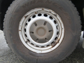 Close-up of a wheel from a 2009 Dodge Sprinter Van featuring a silver rim with multiple holes and a worn tire labeled Wrangler