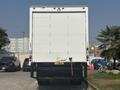 A 2012 Hino 338 truck facing away with a white cargo box and visible tail lights parked among other vehicles