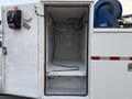 A 2010 Ford F-550 with an open cargo compartment revealing an empty interior space and visible wiring