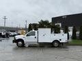 A white 2000 Ford F-450 truck with a utility body featuring multiple storage compartments mounted in the truck bed