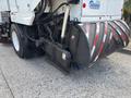 A 2012 International DuraStar 4300 street sweeper with a rotating brush attachment at the front and large wheels