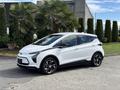 A white 2023 Chevrolet Bolt EV parked on a concrete surface with a sleek design and sporty black wheels