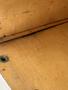 A wooden surface with visible grain and texture featuring two round holes and uneven edges