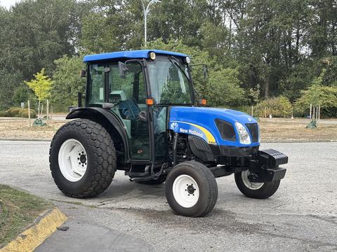 A blue 2009 New Holland T4020 tractor with a cabin and large rear tires parked on a paved surface