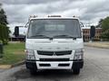 A 2015 Mitsubishi Fuso FE160 truck facing forward with side mirrors extended and the brand name Fuso prominently displayed on the front grille