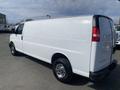 A white 2022 GMC Savana cargo van with a smooth exterior and chrome wheels parked at an angle showcasing its large size and simple design