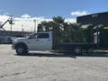 A 2014 RAM 5500 flatbed truck with a white cab and black flatbed loaded with palm trees