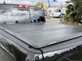 A black 2018 RAM 1500 truck with a hard tri-fold tonneau cover on the bed visible from the rear angle