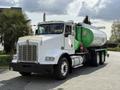 A white 1996 Kenworth T800 truck with a green fuel tank trailer attached and visible chrome grille and headlights