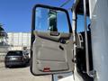 A 2015 Peterbilt 337 truck with the driver's door open showing the interior and dashboard area