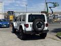 A white 2021 Jeep Wrangler parked with a spare tire mounted on the rear door and rugged off-road tires