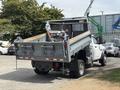 A 2016 RAM 5500 dump truck with its bed raised and filled with construction equipment and tools