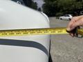 A hand holding a tape measure indicating the length of a 2012 Ford Econoline