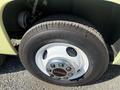 A close-up view of a white wheel and tire of a 1976 GMC Palm Beach with a shiny chrome hubcap featuring the GMC logo and the tire labeled Laredo HP