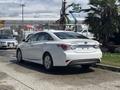A 2014 Hyundai Sonata parked on a driveway with a white exterior and sleek design featuring modern headlights and a distinctive rear end