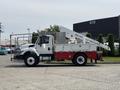 A 2012 International 7300 Workstar truck with a white cab and red compartments featuring an elevated work platform and various tools attached on the side