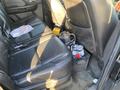 Black leather backseat of a 2007 Cadillac Escalade with scattered items and a container holding various drinks on the floor