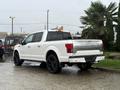 A white 2018 Ford F-150 with a sleek design and black rims parked with its rear facing the viewer