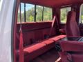 Interior view of a 1995 Ford F-250 featuring red upholstery and seatbelts on a rear bench seat along with a center console