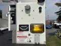 A 2012 International 7300 Workstar with a utility bucket mounted on the chassis featuring safety labels and controls for operation