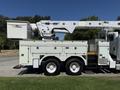 A white 2013 International 7400 bucket truck with a raised aerial lift and storage compartments on the side