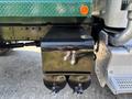 Close-up of a black fuel tank mounted on a green 2015 Peterbilt 337 truck showing two fuel valve openings at the bottom