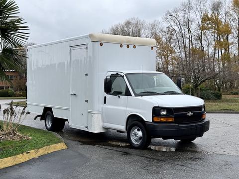 A white 2008 Chevrolet Express cargo van with a boxy rear and a front with a black grille and headlights parked on a paved lot