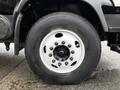 Close-up of a 2007 GMC F7500 truck wheel featuring a black tire with a white rim and multiple bolts in the center