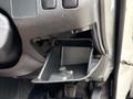 A partially open glove compartment of a 2009 Toyota Hiace showing the plastic interior with a small divider and a slot for storage