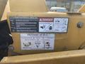 A close-up of a yellow Vermeer Corporation BC1200XL chipper featuring safety warning labels and maintenance checklists attached to its side