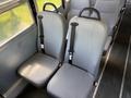 Two gray school bus seats with seatbelts positioned side by side in a school bus interior